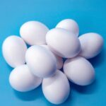 Uova fresche su un tavolo, simbolo di una dieta quotidiana e del dibattito sulla salute del cuore.